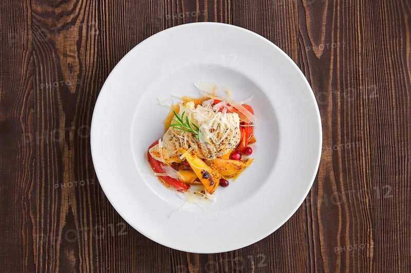 Top voew of fried turkey meat with roasted tomato and bell pepper served with parmesan