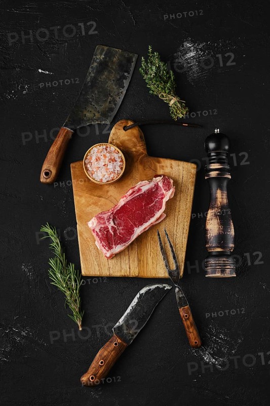 Overhead view of raw strip steak boneless on dark background
