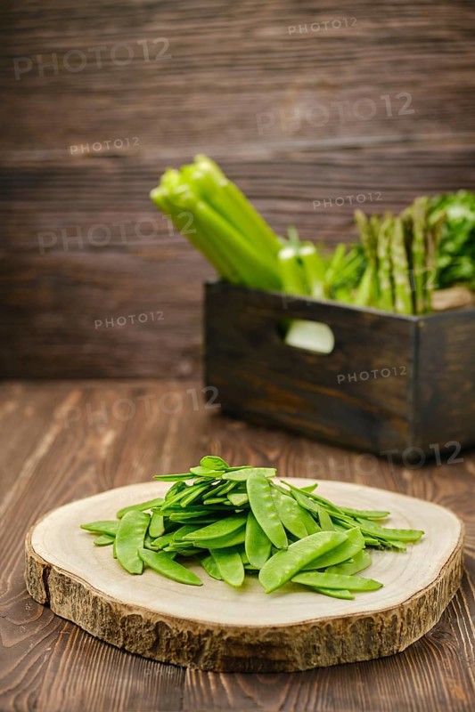 Fresh peas in a pod on wooden cutting board
