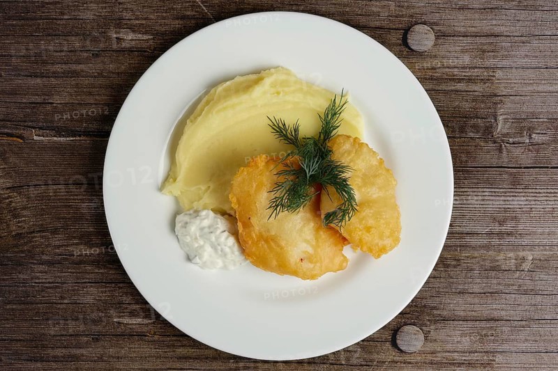 Top view of fish fillet in batter with mashed potato on wooden table