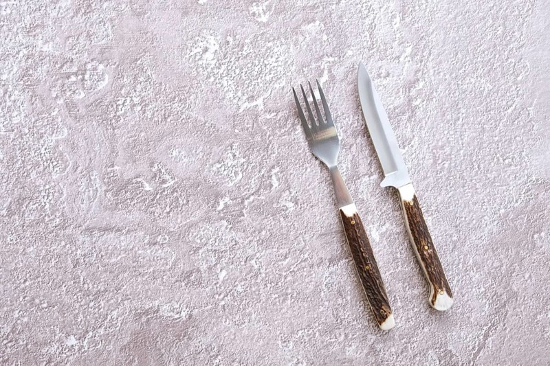 Top view of concrete surface with camping fork and knife with horn handle