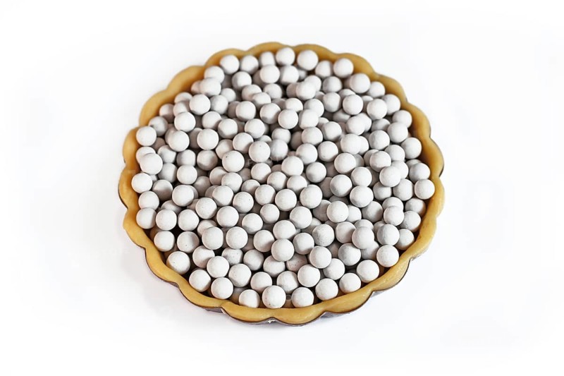 Top view of unbaked tart filled with ceramic pie weights used to keep crust from shrinking during blind baking