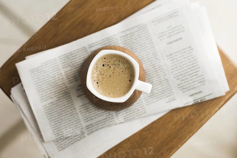 Mug with hot coffee newspapers