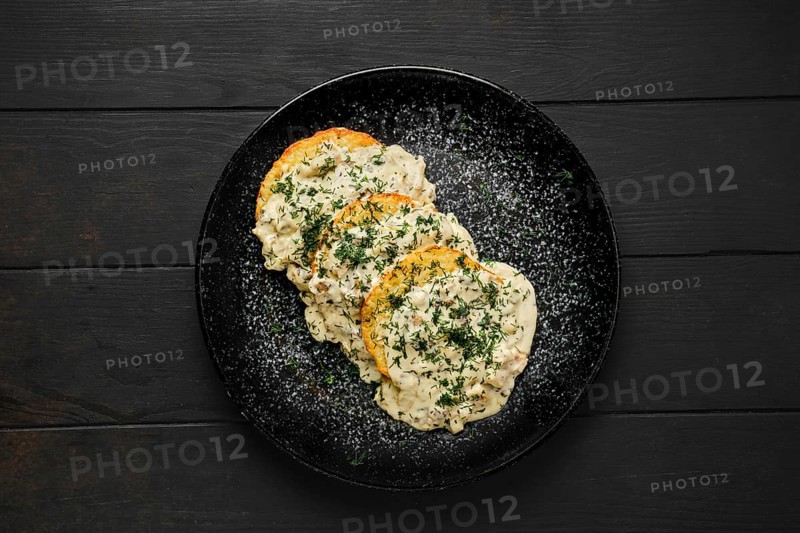 Top view of potato patty with fried boletus and creamy sauce on a plate
