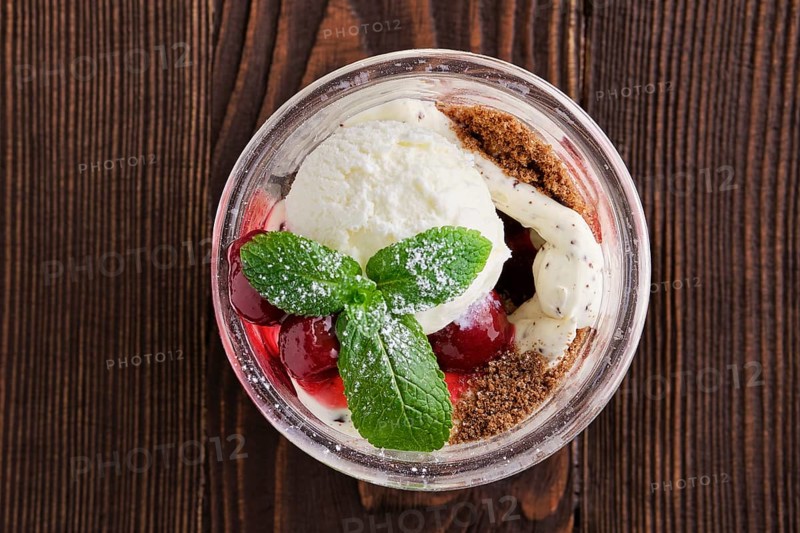 Delicious tiramisu dessert with cherry in rustic pot on dark wooden background