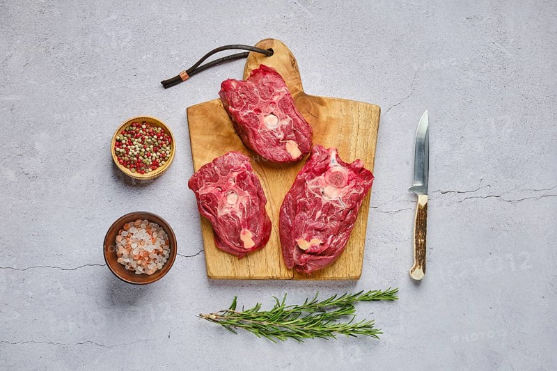Overhead view of raw fresh deer neck with spice and herb over concrete background