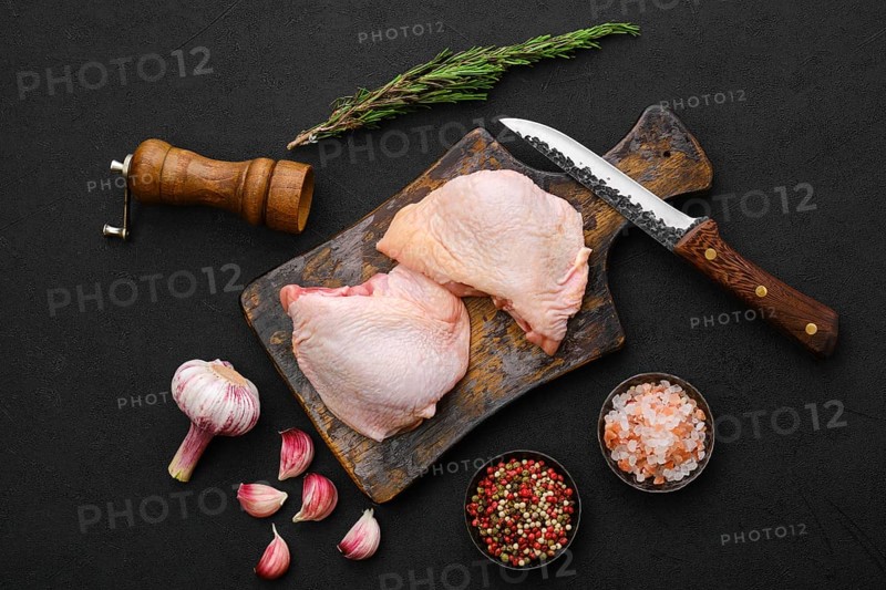 Overhead view of raw chicken thighs on black background ready for cooking