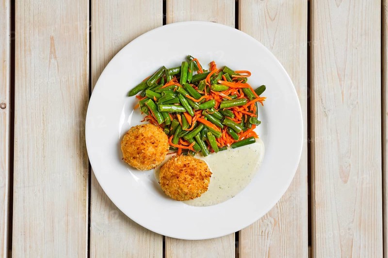 Top view of meatballs in breading served with green bean and spicy carrot