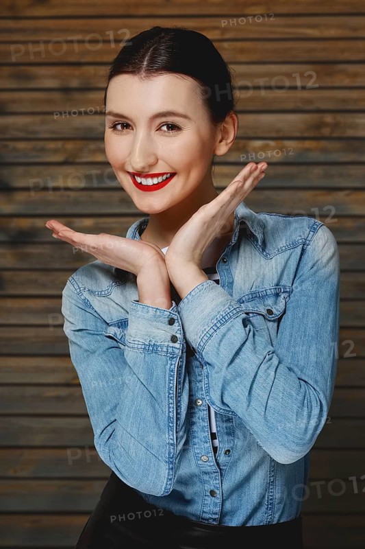 Pretty fashion model in jeans shirt with tan makeup and red mat lips on wooden background