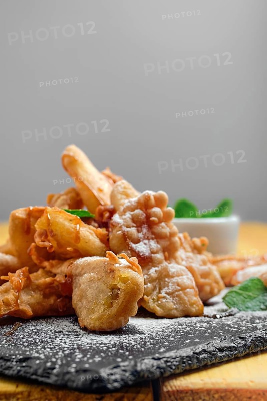 Close up view of deep fried fruits in breading served with caramel and strawberry jam