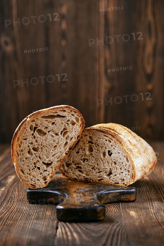 Loaf of artisan sourdough bread with porous texture cut on half