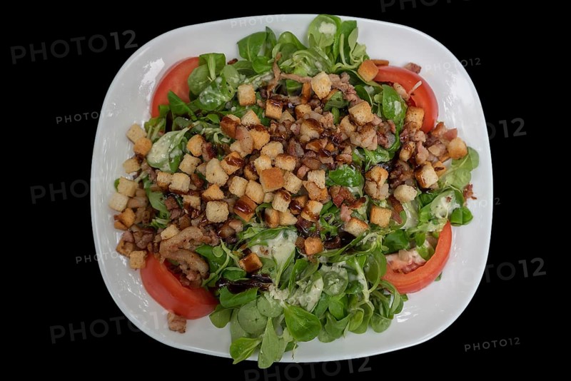 Lamb's lettuce with ham and croutons on a black background