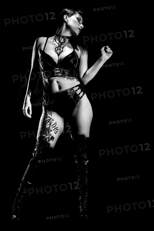 Woman with black hair and tattos in vinyl and latex outfit