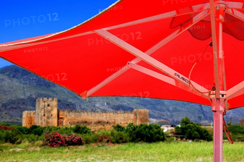 Red parasol and the fortress of Frangokastello on the south coast of the Mediterranean island
