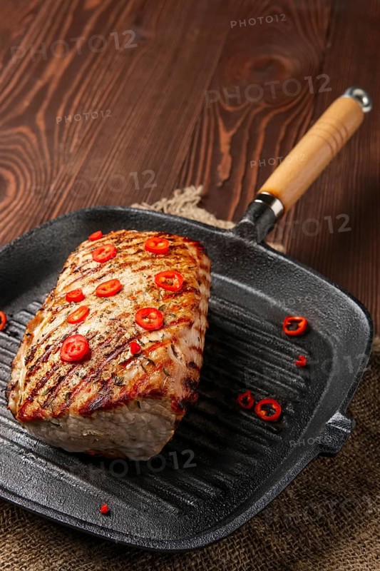 Grilled striploin on cast iron skillet and fried eggplant on wooden background
