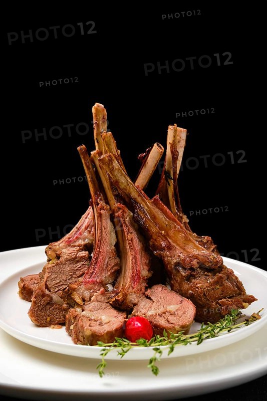 Grilled rack of lamb on a plate with spicy sauce