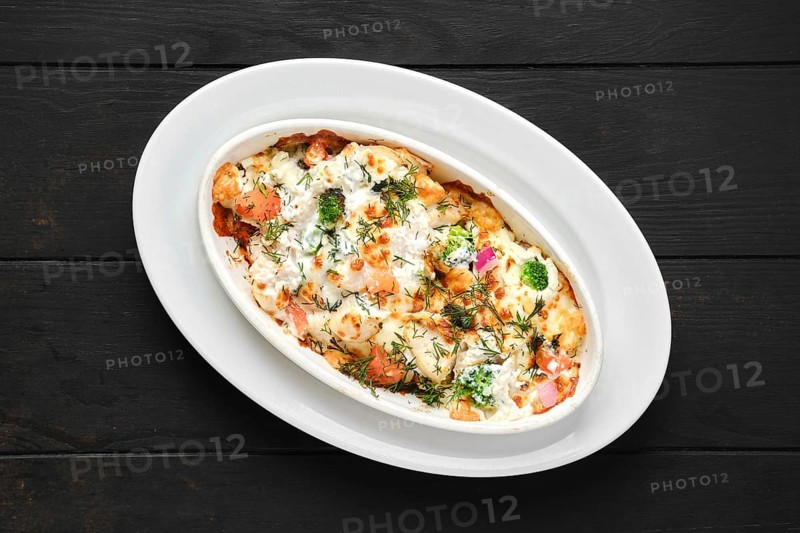 Potato and ham casserole baked in oven with cheese and vegetables