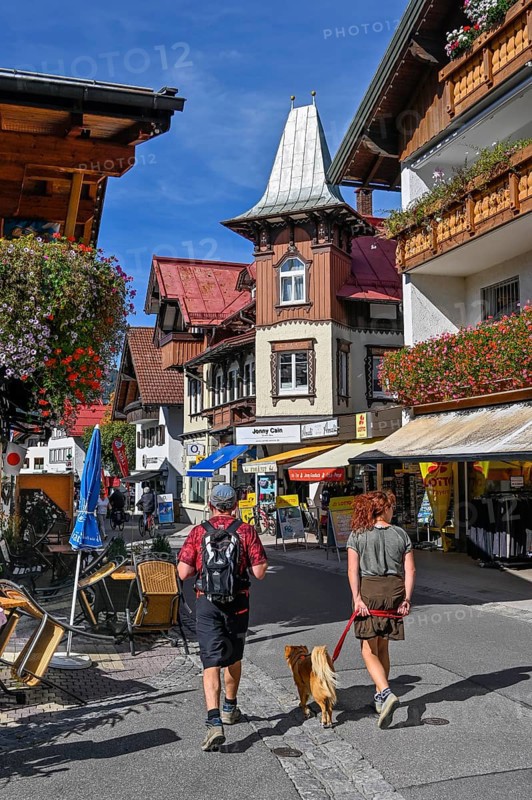 Pedestrian zone with tourists and classic wooden building with wooden shingle facade