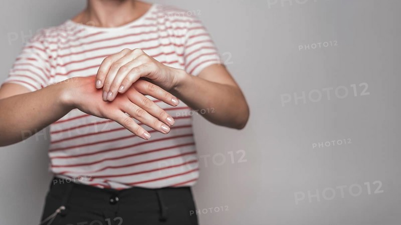 Mid section young woman having pain hand against gray background