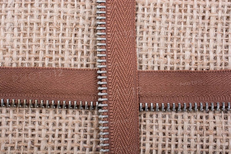 Parts of the brown color zipper on linen canvas background