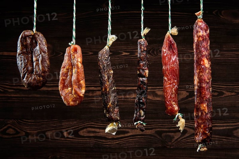 Variety of dried sausage on twine hanging in country wooden barn