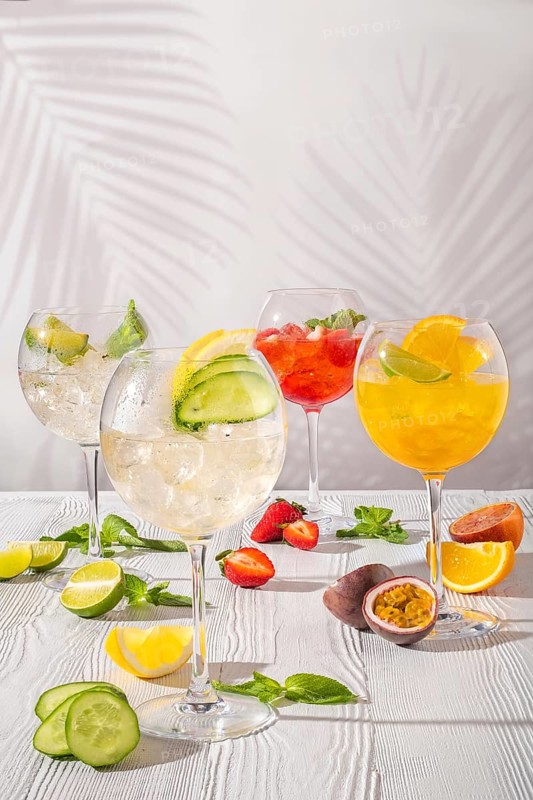 Assortment of cold lemonades in wine glasses on white wooden table in morning sunlight