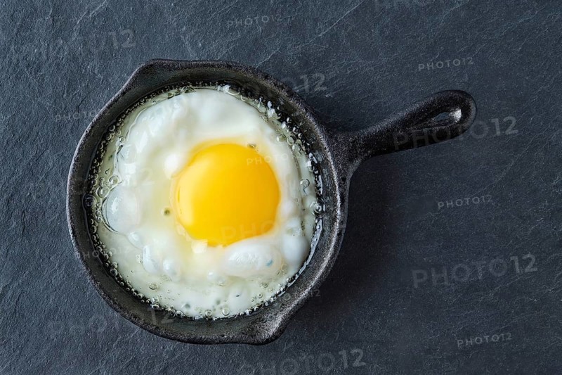 Top view of fried egg in small cast-iron skillet. Making scrambled eggs