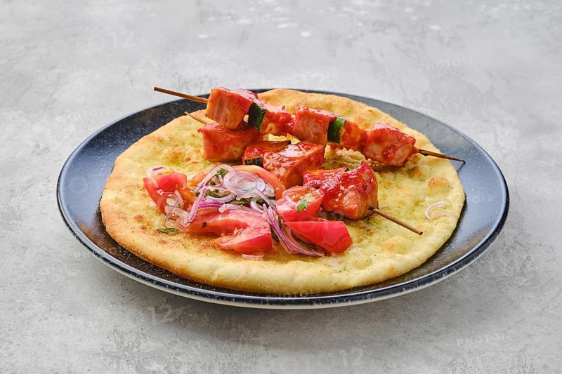 Shashlik served on tortilla with tomato and red onion