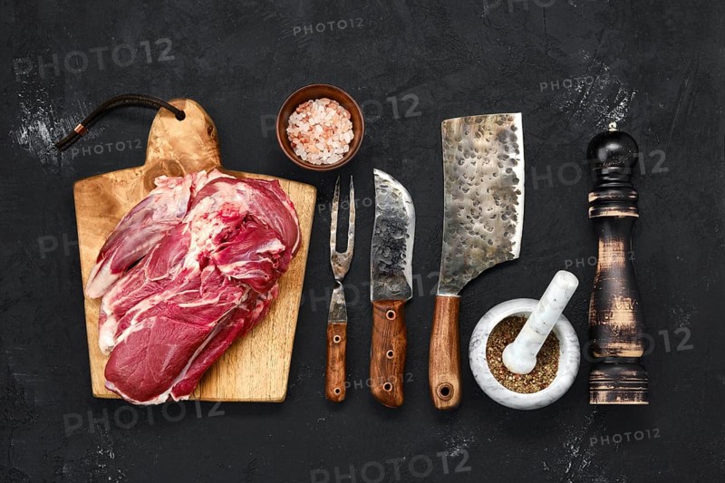 Overhead view of raw lamb shoulder without bone on wooden cutting board