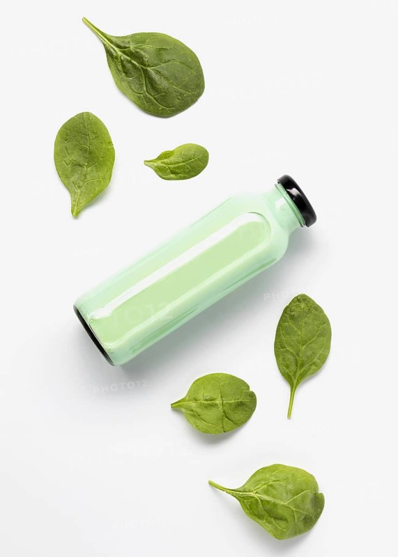 Flat lay juice bottle with spinach leaves