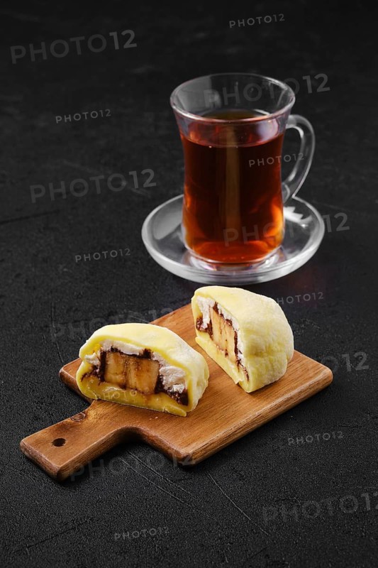 Sweet dessert mochi with banana and chocolate cut on half with fruit tea