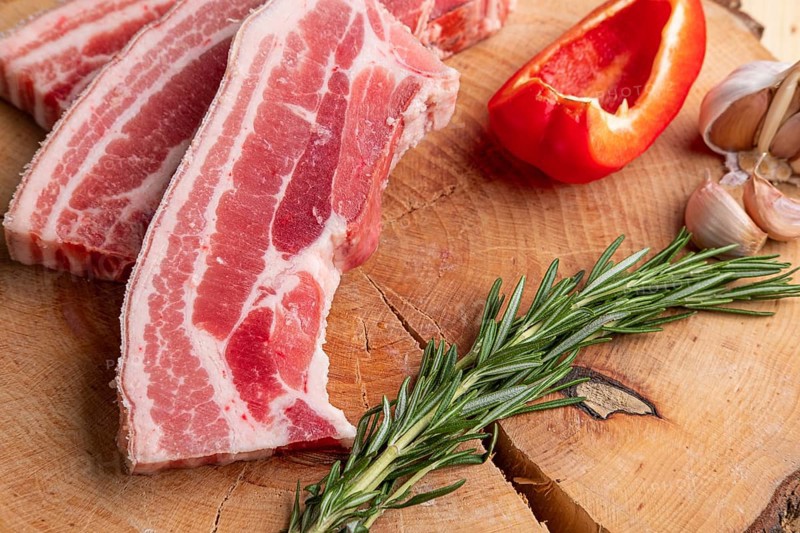 Raw fresh pork brisket slices on wooden cutting board