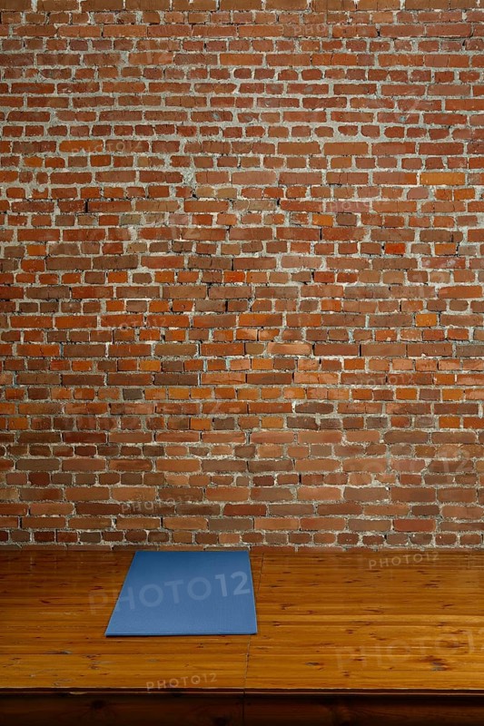 Gym mat on wooden podium with brick wall on background