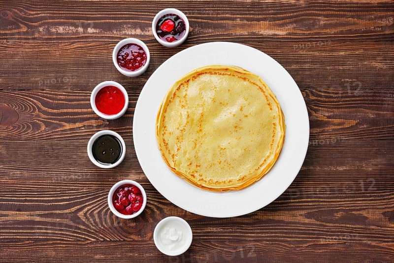 Top view of thin pancakes with assortment of jam and sauce