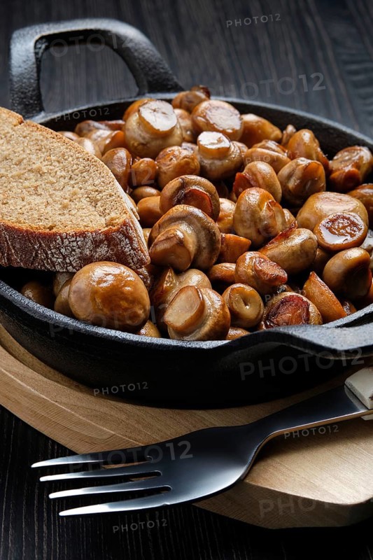 Close up view of cast iron skillet with fried champignon with spice