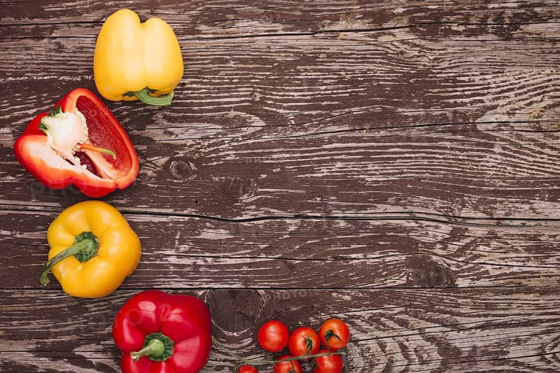 Red yellow bell peppers cherry tomatoes wooden desk