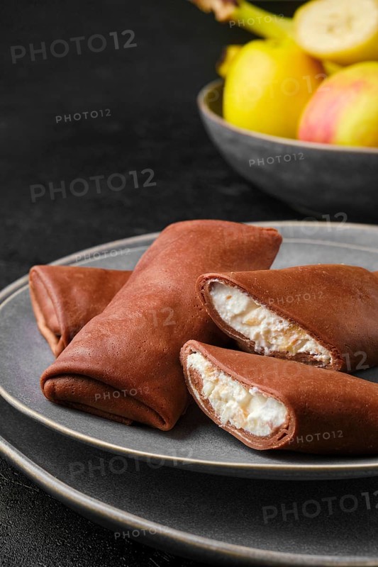 Closeup view of thin chocolate pancakes stuffed with curd