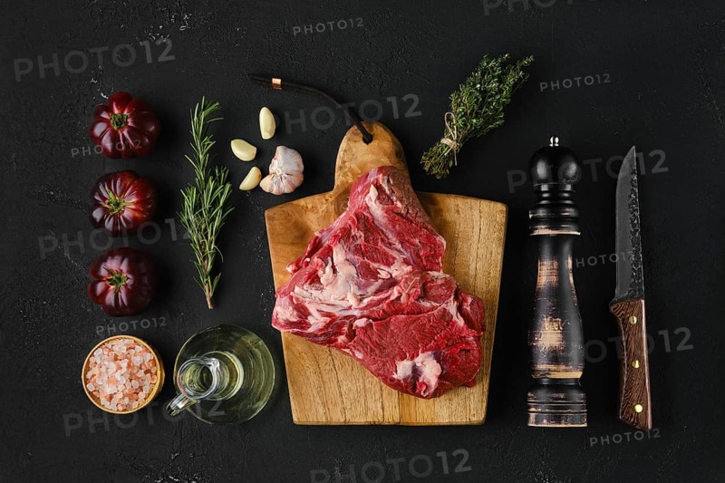 Raw beef top round roast with spices on dark background