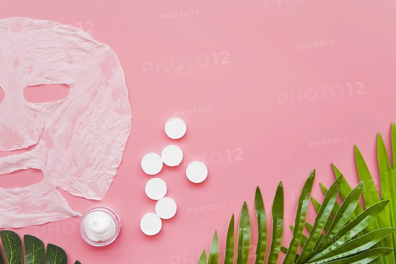 Paper sheet face mask moisturizer green leaves pink background