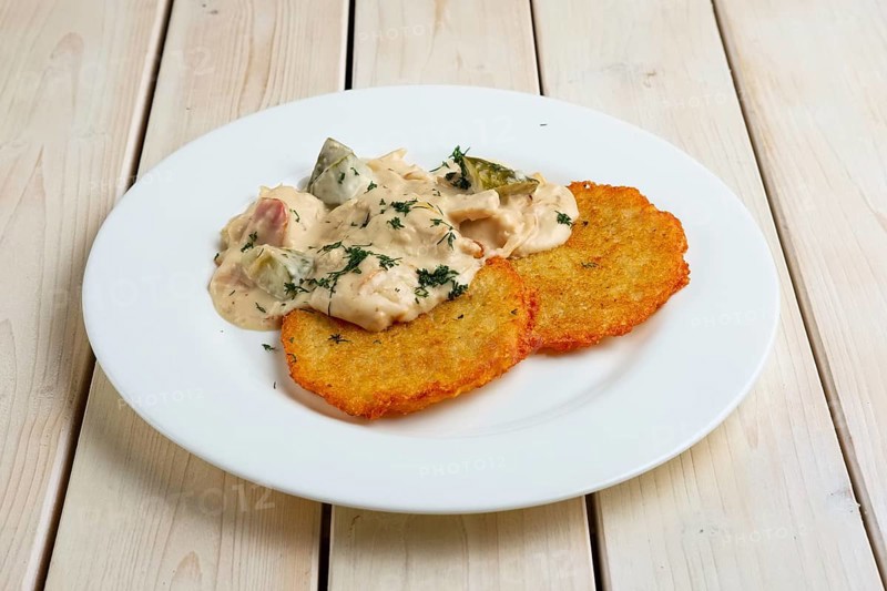 Potato pancakes with flour sauce and pickled cucumber and sausage
