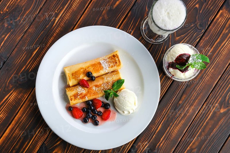 Top view of plate with thin pancakes stuffed with curd and served with berry jam