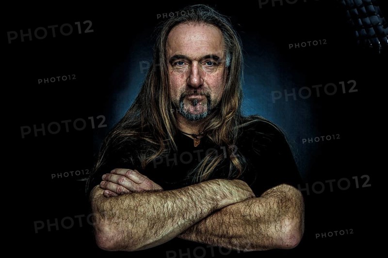 Man with long hair and hand with folded arms