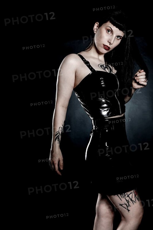 Woman with black hair and tattos in vinyl and latex outfit