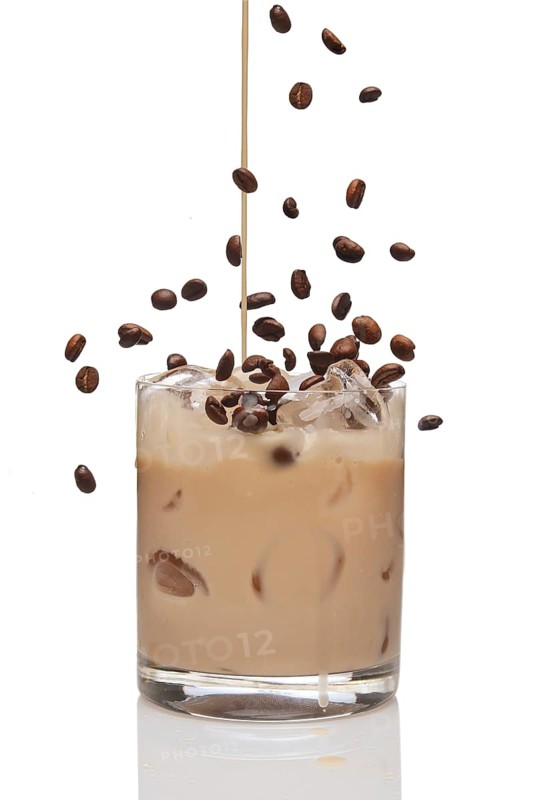 Coffee beans falling into cocktail and Irish creme liqueur pouring in a glass full of ice