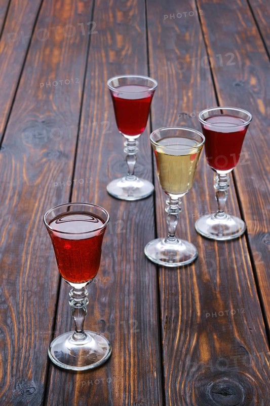 Vodka infused with berries on wooden background