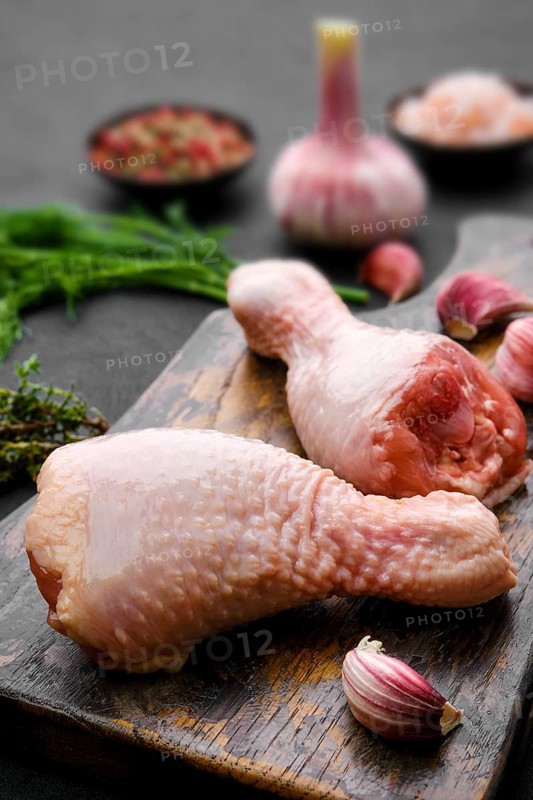 Closeup view of raw chicken legs on wooden cutting board ready for cooking