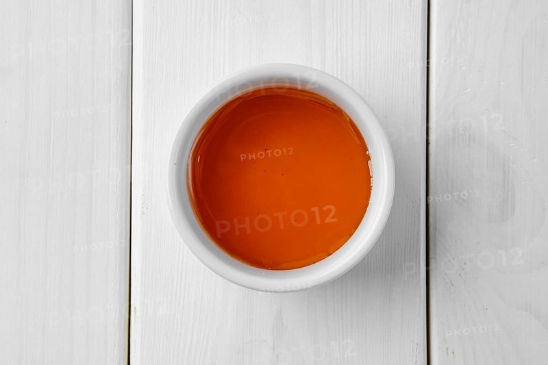 Overhead view of honey in ceramic gravy boat on white wooden table