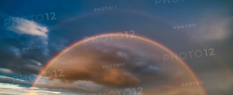 Double rainbow in atmospheric sky with thunderclouds at sunset