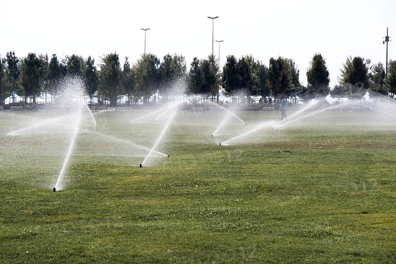 Lawn water sprinkler spraying water over grass in garden