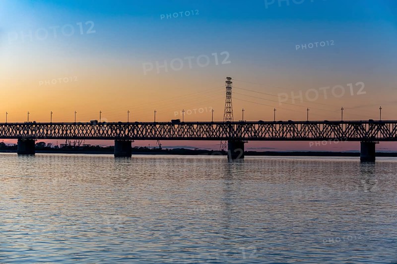 Giant bridge spanning over the Amur river at sunset